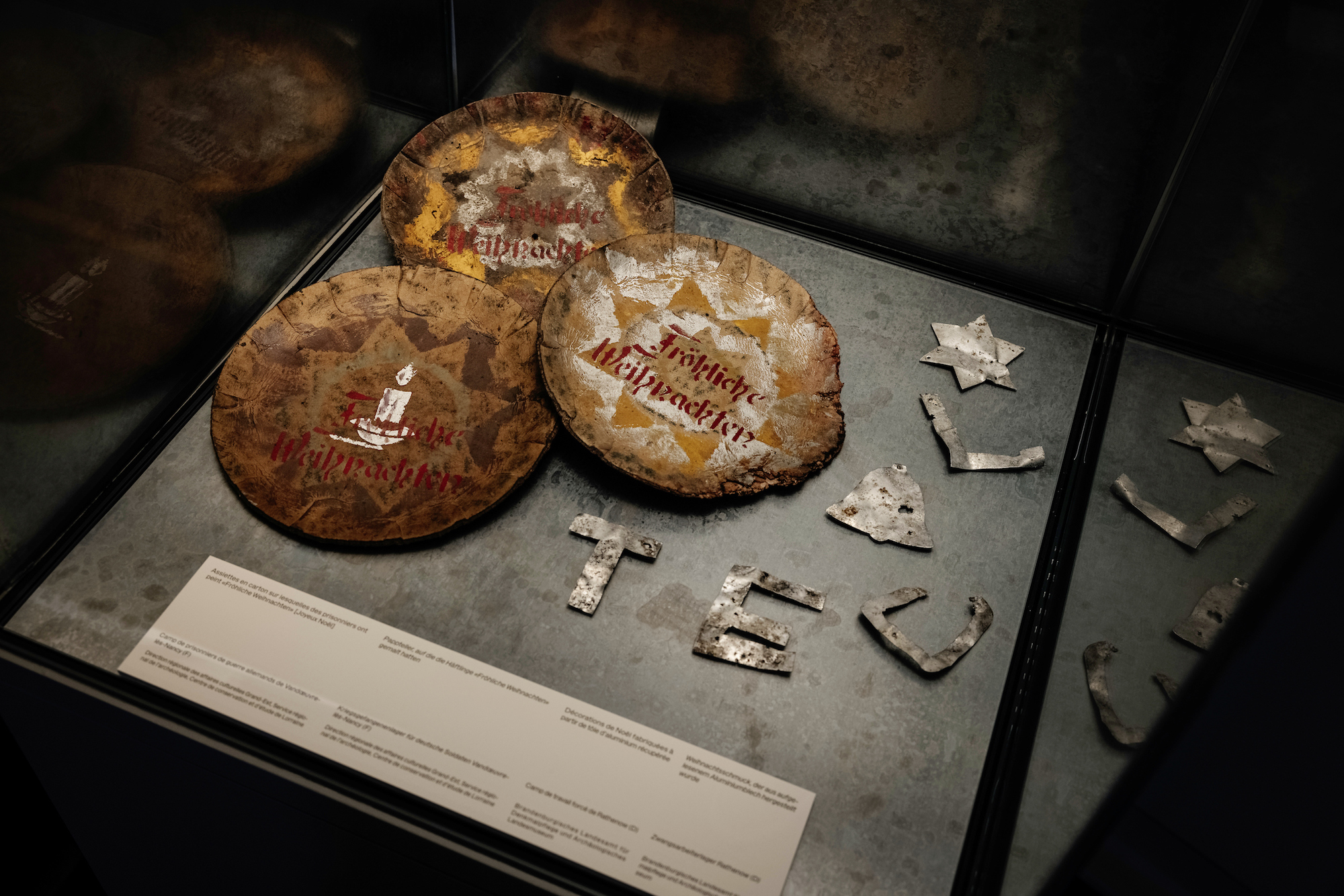 Assiettes en carton sur lesquelles des prisonniers ont peint « Fröhliche Weihnachten » [Joyeux Noël]. Camp de prisonniers de guerre allemands de Vandœuvre-lès- Nancy. Drac Grand-Est, SRA, Centre de conservation et d’étude de Lorraine. Décorations de Noël fabriquées à partir de tôle d’aluminium récupérée. Camp de travail forcé de Rathenow, Brandenburgisches Landesamt für Denkmalpflege und Archäologisches. Landesmuseum. © Laténium, Guillaume Perret