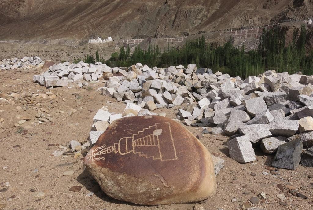 Site rupestre d’Alchi en cours de destruction avec un bloc gravé d’un stupa accompagné d’une inscription en tibétain.