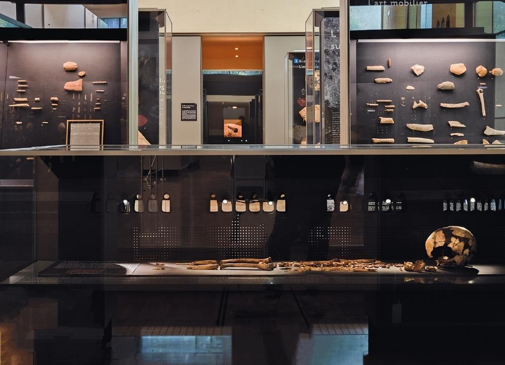 Galerie haute : vue en perspective de l’enfant de La Madeleine, de vitrines d’art mobilier et, tout au fond, au centre, de la célèbre lampe de la grotte de Lascaux.