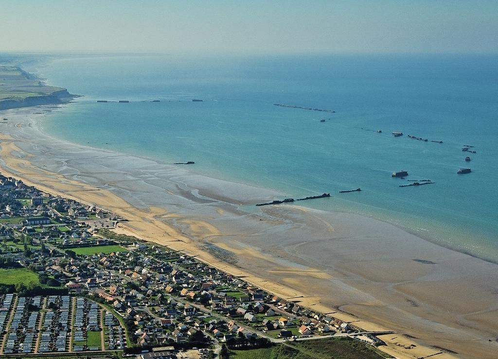 Vue aérienne des vestiges du port artificiel Mulberry B à Arromanches (Calvados), encore partiellement visibles. Il a été assemblé sur place par des ingénieurs militaires britanniques à partir d’éléments préfabriqués dès le soir du 6 juin 1944. Destiné à l’acheminement des armées et du matériel alliés, il reste en service jusqu’au 19 novembre 1944, assurant chaque jour le débarquement de 10 000 à 20 000 tonnes de matériel.