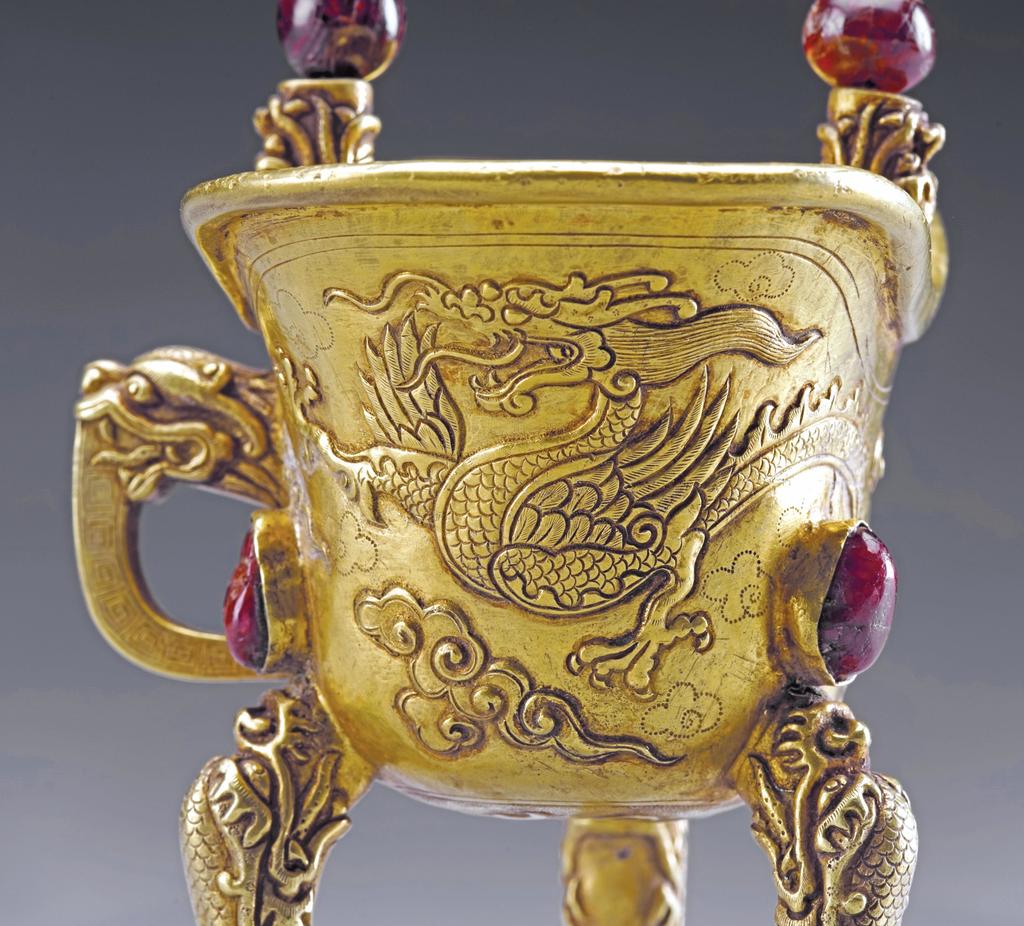 Coupe à libation jue à décor de dragons et son support en forme de montagne, dynastie Ming (1368-1644), règne de Wanli (1573-1620), 1601. Or serti de rubis et saphirs, H. 10,8 (coupe) ; diam. 16,7 cm (plateau) ; poids 342,4 g. Xi’an, musée des Beaux-Arts de Qujiang.