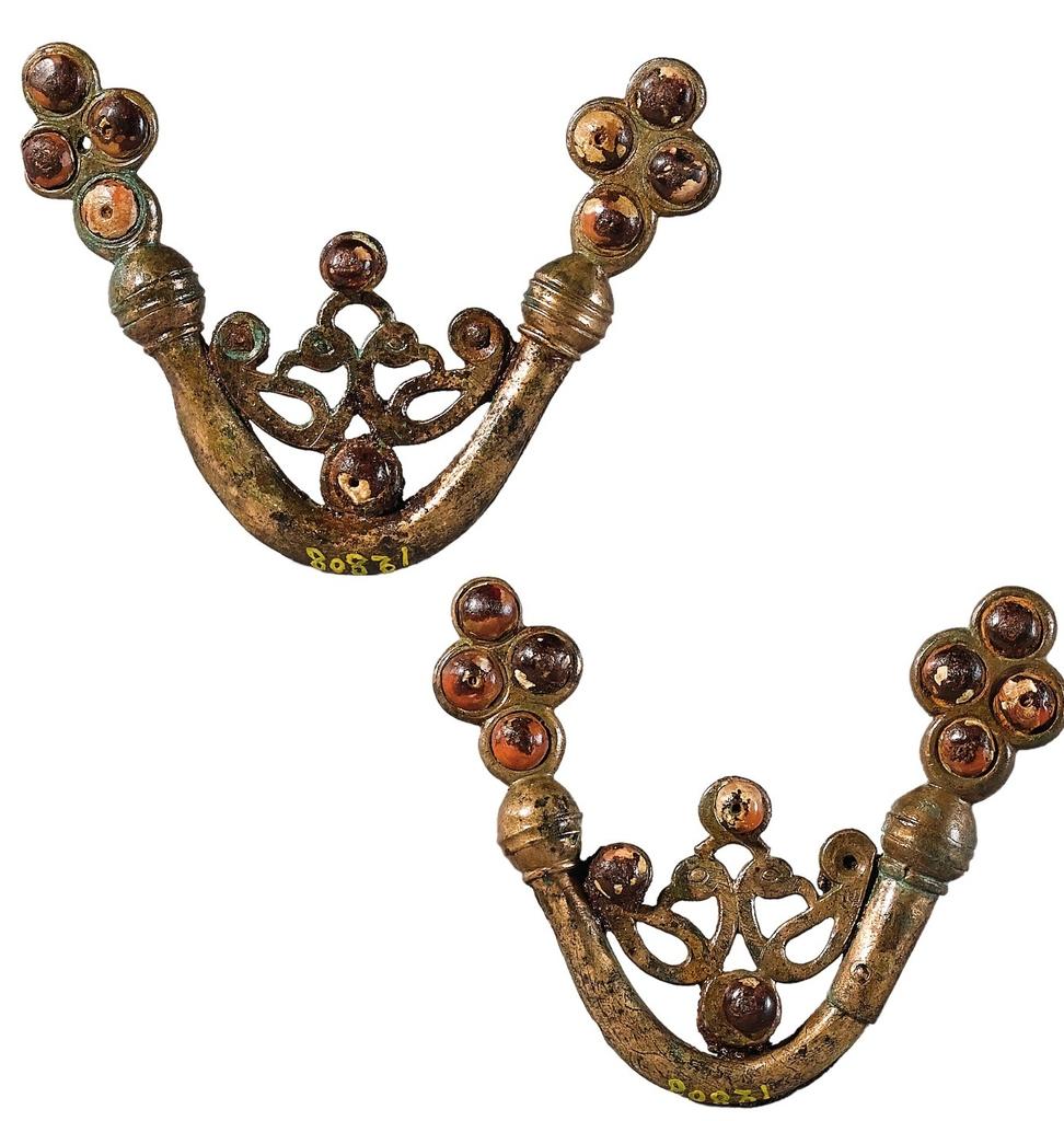 Deux petites appliques en forme de bouterolles d’épées, âge du Fer. Bronze, corail, émail. Saint‑Étienne-au‑Temple. Don de l’empereur au moment de la création du musée de Saint-Germain‑en‑Laye, Saint‑Germain‑en‑Laye, musée d’Archéologie nationale.