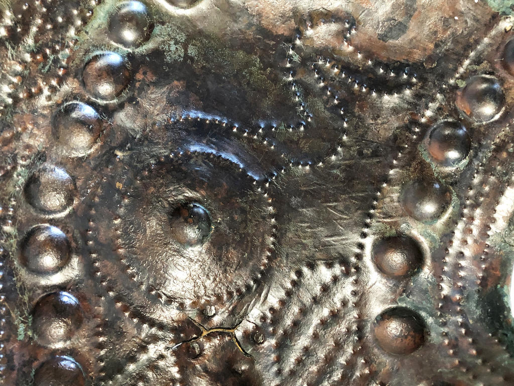 Détail de l’une des cuirasses de l’Âge du bronze final de Fillinges(Haute‑Savoie). Vue au revers du décor de bossettes et de pointillé ainsi qu’une réparation. Musée d’art et d’histoire de Genève.