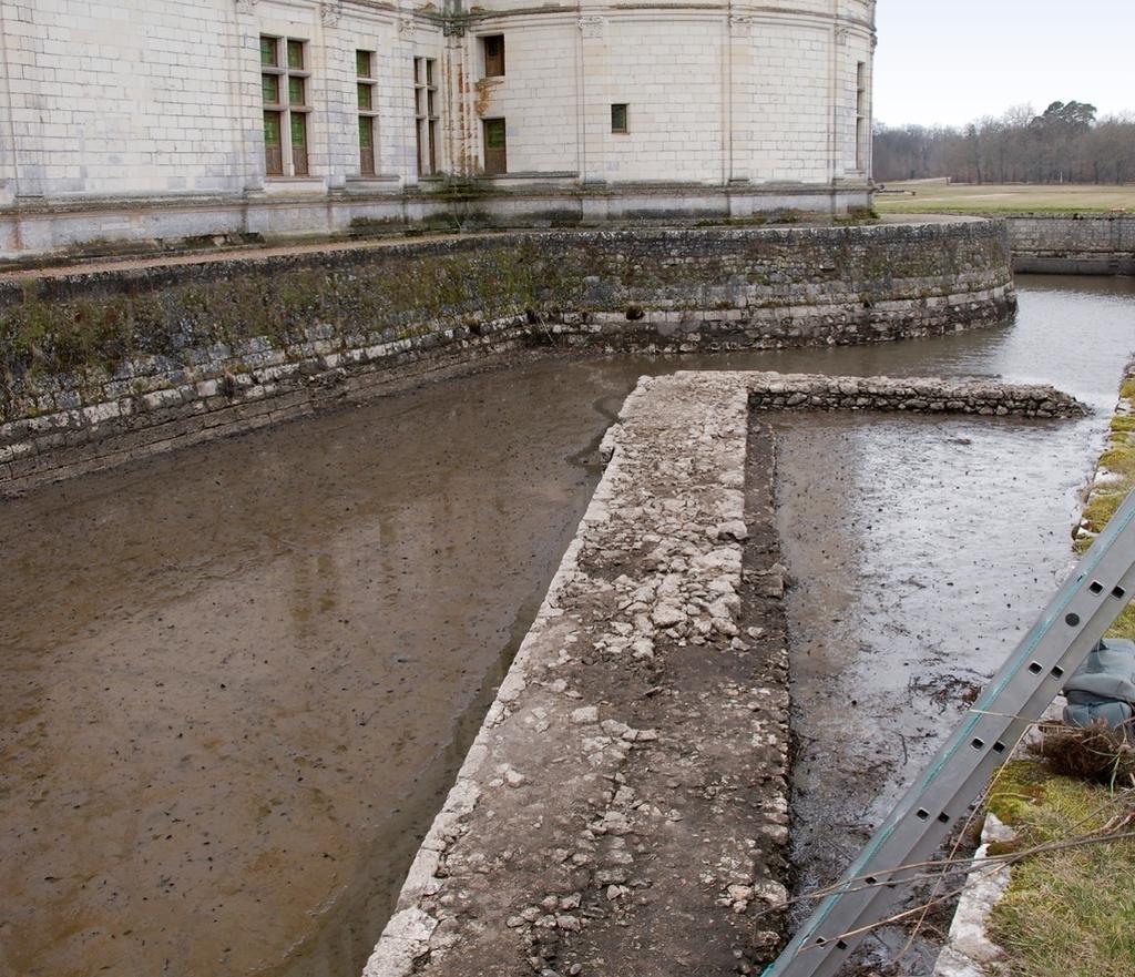 Les douves à l’est du château. Comblées au XIXᵉ siècle, elles furent remises en eau dans les années 1970. Les maçonneries visibles correspondent à la base du mur de terrasse qui formait la limite ouest du « Grand Jardin » du XVIᵉ siècle.