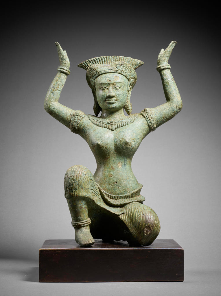 Divinité féminine agenouillée, support de miroir (?). Époque angkorienne, première moitié du XIIe siècle, Prasat Bayon, Angkor Thom, province de Siem Reap, Cambodge, bronze, H. 34 cm. Musée national du Cambodge à Phnom Penh.