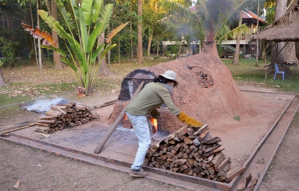 Cuisson expérimentale dans un four khmer reconstitué sur la base des données archéologiques. Choi Myongduk, doctorante, lors de l’opération On Fire en décembre 2018 au centre de l’EFEO à Siem Reap.