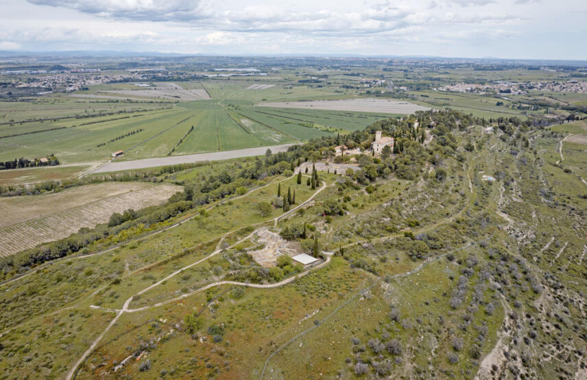 Vue aérienne du site d’Ensérune en direction de la dépression de Montady, drainée durant le Moyen Âge. Le musée est au centre.