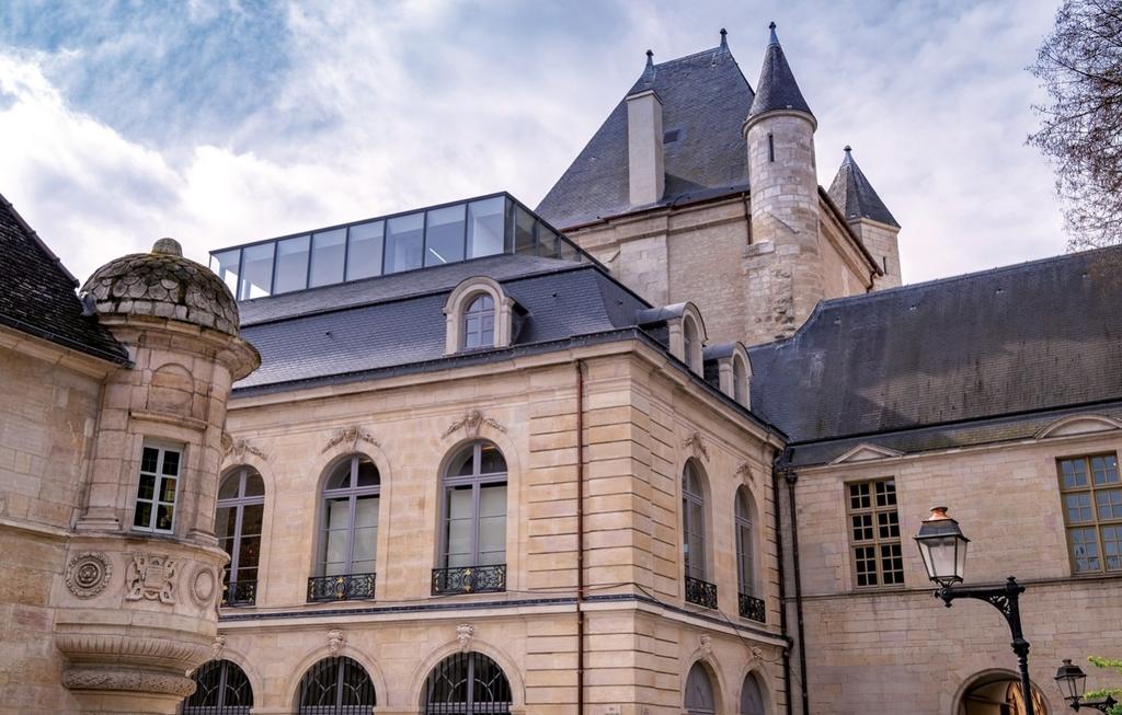 L’extension vitrée conçue par Yves Lion au sommet de l’aile XIXᵉ, le long de la rue Longepierre, accroît la surface d’exposition et offre un panorama d’exception sur le cœur de ville.