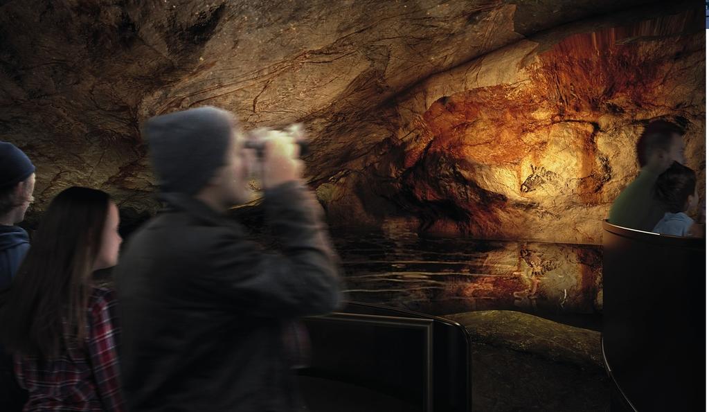 Les visiteurs circulent dans la restitution de la grotte à bord de modules d’exploration.